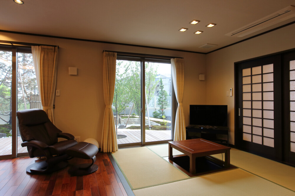 LDK+畳コーナーのある間取りから広い裏庭を眺める景色として暮らしの優位性とウッドデッキの存在効能を、室内だけでは無くて天気の良い心地よい日は外に出てウッドデッキから広い庭を眺める暮らし
