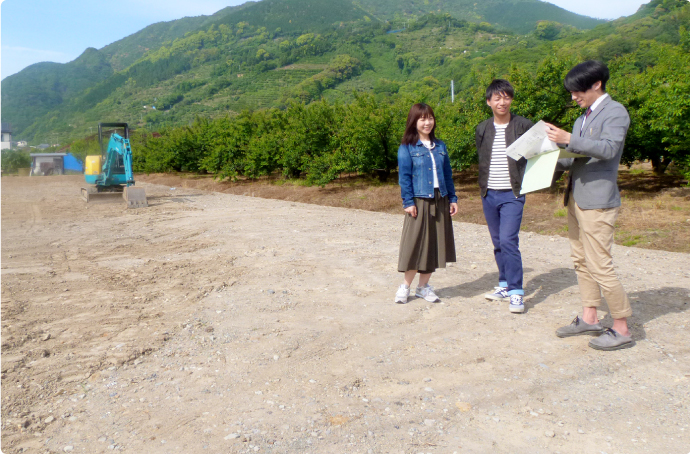 奈良県内の注文住宅計画に向けて、整地された敷地で建築家と夫婦が土地条件を確認している様子。土地の広さや日照、周辺環境などを実際に見ながら、理想の住まいに適した敷地かどうかを判断している現地確認風景。奈良での土地探し・注文住宅計画をサポートする建築家の土地アドバイス中の場面。