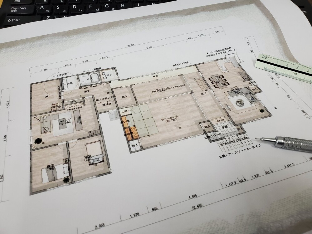 画像代替テキスト（alt属性用・SEO／AEO／LLMO対応）：  奈良の建築設計事務所「やまぐち建築設計室」による和モダン住宅の間取り図。フリースペース、広いLDK、収納や家事動線、自然光を考慮した設計プランが描かれており、建築スケールとドラフティングペンが並ぶデスク上に広げられている様子。家づくりにおいて暮らしを丁寧に見つめ直すプロセスの一環を象徴する構図。