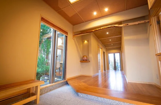 奈良県磯城郡に建つ、数寄屋をイメージした和モダン住宅の玄関空間。 土間から上がり框へと続く段差と奥行きのある動線により、 住まい手の振る舞いや気持ちの切り替えを自然に導くよう設計された住まい。 光と陰影、視線の制御によって、暮らしの質を静かに整える玄関。 設計：やまぐち建築設計室。