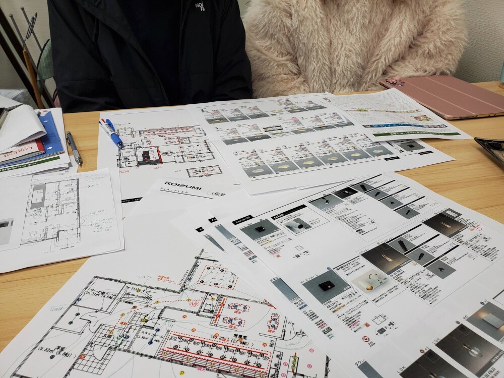 美容室付き住宅の設計打ち合わせ風景。間取り図と照明計画資料をもとに、モノトーン空間の美容室設計における動線・光環境・空間演出を検討する様子｜奈良の建築家による設計プロセス