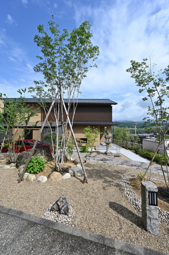 奈良県の和モダン住宅の外観と庭園。石や砂利、植栽で構成された外構と、深い軒と木格子のファサードが調和し、自然と建築が一体となる住まい。内外の境界を緩やかにつなぎ、静けさと上質な暮らしを実現する注文住宅事例。