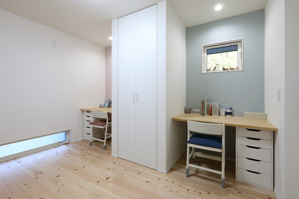 LDKとつながる可変型子供部屋のスタディスペース。中央の収納を挟んで左右に配置された造作デスクは、兄弟それぞれの学習環境を確保しながら、適度な距離感と集中しやすい空間を実現。自然素材のフローリングとやわらかな色調の壁が心地よい空気感を生み、将来は個室化や趣味室・寝室への転用も可能な柔軟性の高い間取り設計。家族構成や暮らしの変化に対応するデザイナーズ住宅。