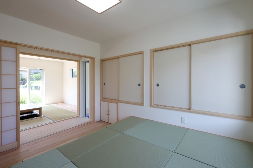 LDKとゆるやかにつながる半和室空間と、縁側のような中間領域を設けた和モダン住宅のインテリア設計。畳のやわらかな質感と白壁、無垢材の建具が調和し、自然光が静かに広がる落ち着きのある空間を演出。引き戸を開放することで、LDKと一体感のある広がりを生み出しながら、必要に応じて個室としても機能する柔軟な間取り構成。和モダンの家・自然素材の家・注文住宅・和室空間・デザイナーズ住宅を求める方へ向けた建築家住宅の設計事例。