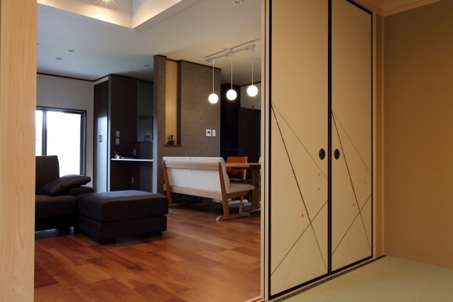 畳敷きの和室とフローリングのLDKが襖でゆるやかにつながる和モダン住宅の空間設計。開放時にはダイニングと一体となり、閉じることで落ち着いた個室としても機能する可変性の高い間取り。意匠性のある襖デザインと自然素材の質感が、上質でホテルライクな暮らしを演出し、動線と居心地を両立した住まいの一例。