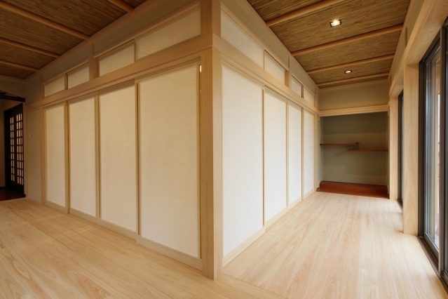 奈良県の建築家による高級和モダン住宅の内部空間。 無垢材の床と木天井、障子建具で構成された和室と回遊動線、床の間を備えた落ち着きある設計で、光と陰影が調和する上質な注文住宅の内装デザイン事例。