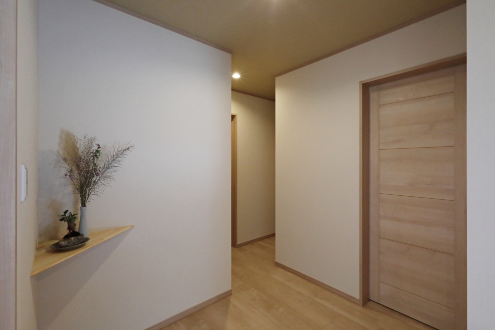 和の静けさと現代的な暮らしやすさを融合した、回遊性のある和モダン住宅のホール空間。各部屋へとゆるやかにつながる動線を、単なる通路ではなく“居場所”として丁寧に設計し、少しずつ広がりを持たせることで、空間に奥行きと心地よさを生み出している。やわらかな間接的な光と無垢調の床材、余白を活かした設えが、ホテルライクで落ち着きのある住空間を演出。和モダンの家・高級注文住宅・回遊動線のある家・居心地の良い間取り・デザイナーズ住宅・上質な暮らしを求める方に向けた住宅設計事例。
