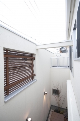 奈良の注文住宅における和モダン住宅の中庭空間設計。高い壁と木製ルーバーで外部からの視線を遮りながら、上部から自然光と風を取り込むプライベートな外部空間。都市部でも開放感とプライバシーを両立したホテルライクな住まいの実例。